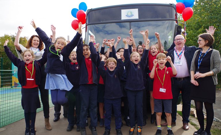 Children celebrate the arrival of the new bus